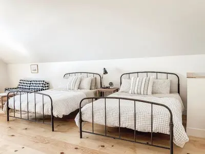 two beds in a bedroom with white walls at Homestead Barn Loft in Sonora