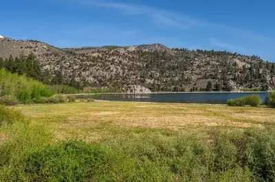 a field with a lake in front of a mountain at Lakefront Mountain Retreat in June Lake
