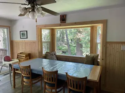a dining room with a table and chairs and a window at Big Cabin on the Creek in Camp Connell