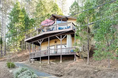 a house with a wrap around deck in the woods at Enchanted Woodland Cabin Near Yosemite with Fire Pit in Groveland