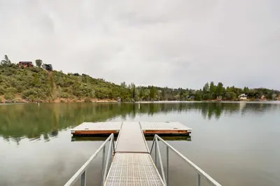 a dock on a lake with trees on the shore at Enchanted Woodland Cabin Near Yosemite with Fire Pit in Groveland