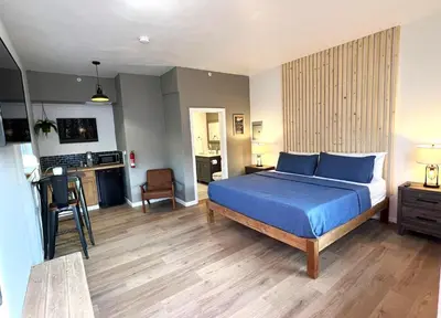 a bedroom with a blue bed and a kitchen at Wofford Village Studios in Wofford Heights