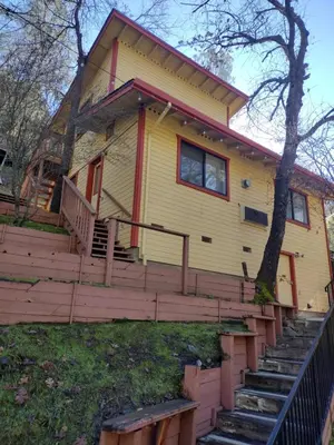 a yellow house with stairs leading up to it at Yosemite Gatekeeper's Lodge in El Portal