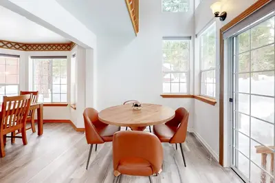 a dining room with a table and chairs and windows at Blue Skies & Bay Bliss in Carnelian Bay