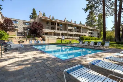 a hotel with a swimming pool with lounge chairs at Lakeland Village 406 - The Lake Escape in South Lake Tahoe