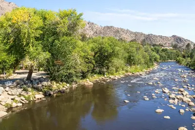 a river with rocks and trees and mountains in the background at Brand new Cabins in Kernville