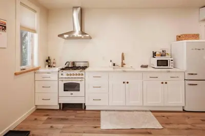 a kitchen with white cabinets and a white refrigerator at Timberwood Cottage in Downtown Twain Harte in Twain Harte