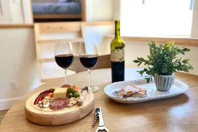 a table with two glasses of wine and a plate of food at Timberwood Cottage in Downtown Twain Harte in Twain Harte
