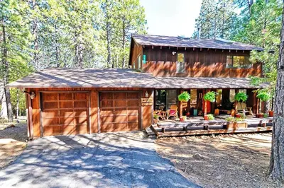 a large wooden cabin with a porch in the woods at *Pinecone Hollow*Hot Tub & Game Room, Families in Arnold