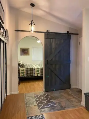 a barn door in a room with a bed at Cedar Oasis - Pet Friendly Cabin w Fireplace, Games and Wifi - 5 min to Big Trees in Arnold