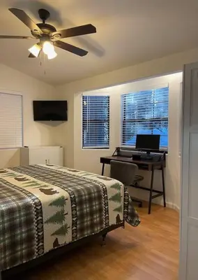a bedroom with a bed and a desk with a computer at Cedar Oasis - Pet Friendly Cabin w Fireplace, Games and Wifi - 5 min to Big Trees in Arnold
