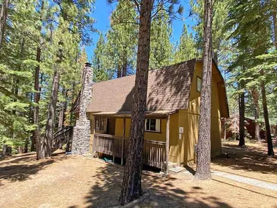 a yellow house in the middle of a forest at 1629 Pioneer Trail home in South Lake Tahoe