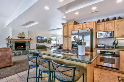 a kitchen with a island with bar chairs and a fireplace at 1759 Venice Drive home in Tahoe Keys
