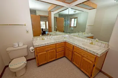 a bathroom with two sinks and a toilet and a mirror at 2293 Marshall Trail home in South Lake Tahoe