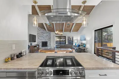 a kitchen with a stove and a living room at Fun & Air Conditioned Lake Tahoe 3 BR/2.5 BA Home in Incline Village