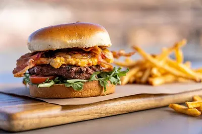 a hamburger on a wooden cutting board with french fries at Under Canvas Yosemite in Groveland