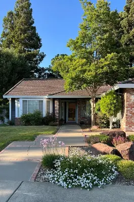 a house with flowers in front of a driveway at Serene Modern Family Getaway Near Midtown Downtown and Folsom Lake in Elk Grove