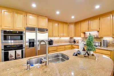 a kitchen with wooden cabinets and stainless steel appliances at Gas Grill and Pool Table Cabin Near Calaveras Park! in Arnold