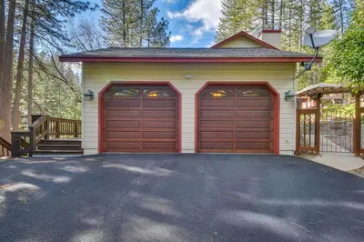 a garage with two garage doors and a driveway at Gas Grill and Pool Table Cabin Near Calaveras Park! in Arnold