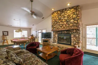 a living room with a stone fireplace and a table at Upper Cascades in Yosemite West
