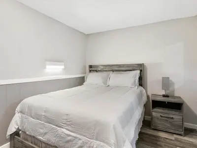 a white bedroom with a large bed and a night stand at Charming Retro Property 8 in Sparks