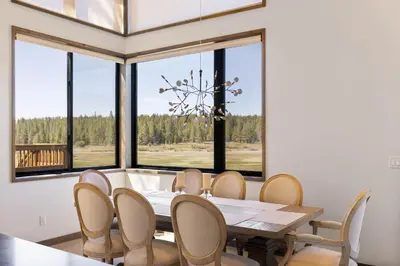 a dining room with a table and chairs and windows at Meadowlark in Tahoe Donner - Modern 4BR w great views, hot tub & HOA amenities in Truckee