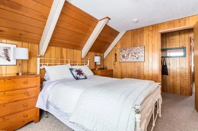 a bedroom with a white bed and wooden walls at Quaint Cabin in Serene Lakes - Close to Skiing! in Soda Springs