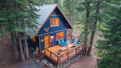 a blue house in the middle of a forest at Minutes to Skiing Lake Hot Tub Fire Pit Deck Indigo Owl by AvantStay in Homewood