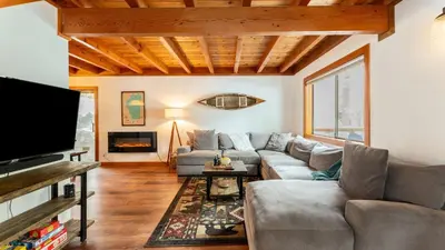 a living room with a couch and a tv at Minutes to Skiing Lake Hot Tub Fire Pit Deck Indigo Owl by AvantStay in Homewood