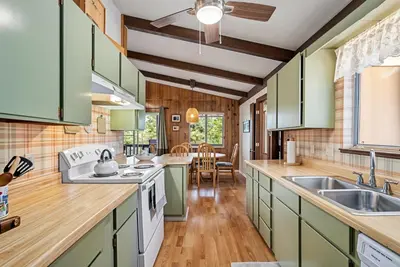 a kitchen with green cabinets and wooden floors at Tranquil Retreat - Home with Spacious Deck & Grill home in Groveland