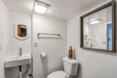 a bathroom with a toilet and a sink and a mirror at Tranquil Retreat - Home with Spacious Deck & Grill home in Groveland