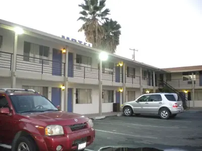 two cars parked in a parking lot in front of a building at Wasco Inn in Wasco