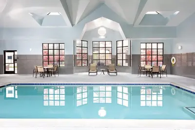 a swimming pool with tables and chairs in a building at Staybridge Suites Sacramento-Folsom by IHG in Folsom