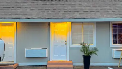 a house with yellow doors and a potted plant at Budget Motel in Gilroy
