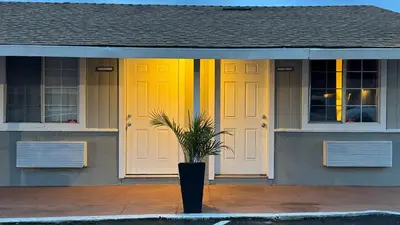 a house with two yellow doors and a potted plant at Budget Motel in Gilroy