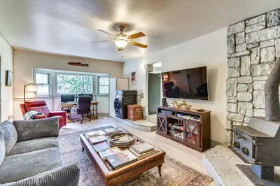 a living room with a fireplace and a stone wall at Lake Access and Hot Tub Pet-Friendly Arnold Home in Arnold