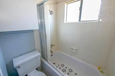 a bathroom with a toilet and a tub and a window at Ala Wai BoulevardApartment 23 in Lake Valley