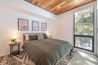 a bedroom with a large bed and two windows at Modern Eco Retreat with Hot Tub and Views in Truckee