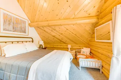 a bedroom with a bed in a wooden cabin at Mountain Cabin with Hot Tub 4 Mi to Shaver Lake! in Shaver Lake