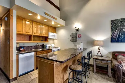 a kitchen with a bar with stools and a couch at Lofted Retreat in The Village! condo in Truckee