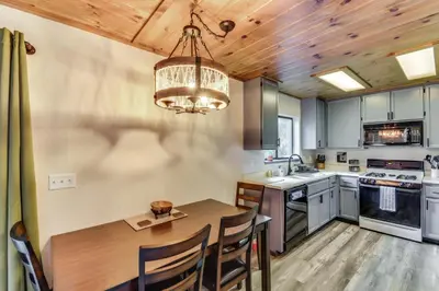 a kitchen with a dining table and a chandelier at 2 Mi to Mi-Wuk Village Cabin with Large Deck in Twain Harte