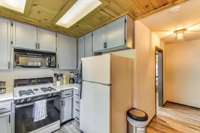 a kitchen with white cabinets and a refrigerator at 2 Mi to Mi-Wuk Village Cabin with Large Deck in Twain Harte