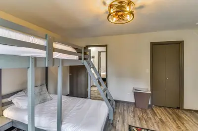 a bedroom with two bunk beds and a chandelier at 2 Mi to Mi-Wuk Village Cabin with Large Deck in Twain Harte