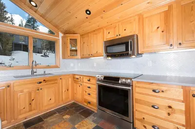 a kitchen with wooden cabinets and a microwave at Mineral Springs 3 BR w Hot tub Available in Alpine Meadows in Olympic Valley