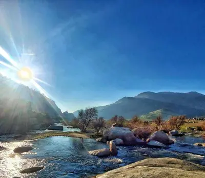 a river with rocks and the sun in the sky at Sequoia Villa in Visalia