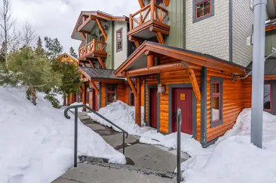 a log home with a red door in the snow at Cabins 24 in Mammoth Lakes