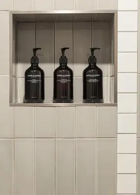 a shelf with four bottles on it in a bathroom at Best Bet Motor Lodge in Reno