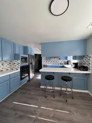 a kitchen with blue cabinets and two stools in it at Entire 3 BR & 2 BA house for business and family in Modesto