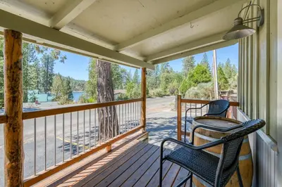 a porch with two chairs and a view of a lake at #3 Cottage Like Suite With Private Hot Tub in Bass Lake
