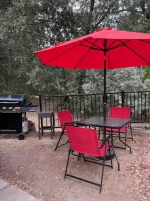 a table and chairs with a red umbrella and a grill at Knotty Pines Lodge in Bass Lake Annex